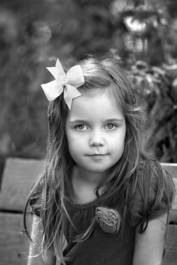 siyah ve beyaz dışında bir bankta oturan küçük kız portresi