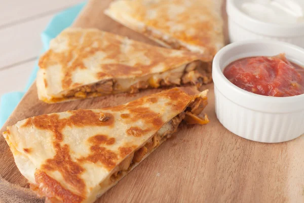 Homemade chicken mexican quesadilla on wooden chopping board with a side of salsa — Stock Photo, Image