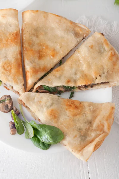 Mushroom spinach quesadilla cut into pieces and arranged on white plate, overhead shot — Stock Photo, Image