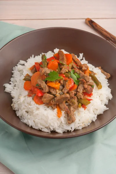 Eine braune Schüssel mit weißem Reis unter Rühren braten Rindfleisch mit Paprika, Spargel und Karotten — Stockfoto