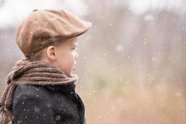 Um menino criança vestida quente olhando para a frente e pensando enquanto sua neve — Fotografia de Stock