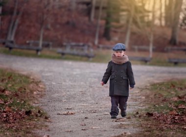 soğuk bir günde bir yol bir parkta yürürken bir şapka giymiş ciddi küçük çocuk