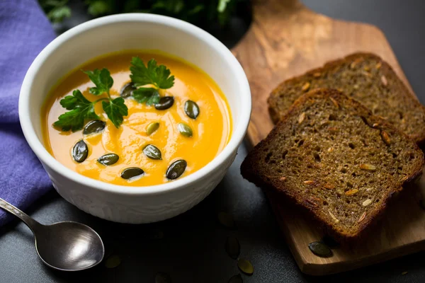 Soupe de citrouille dans un bol avec des graines et du pain frit — Photo