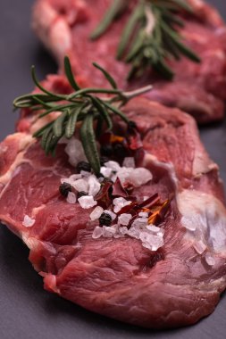 Otlar ve biberiye arka plan siyah bir masada ham sığır eti biftek. Seçici odak