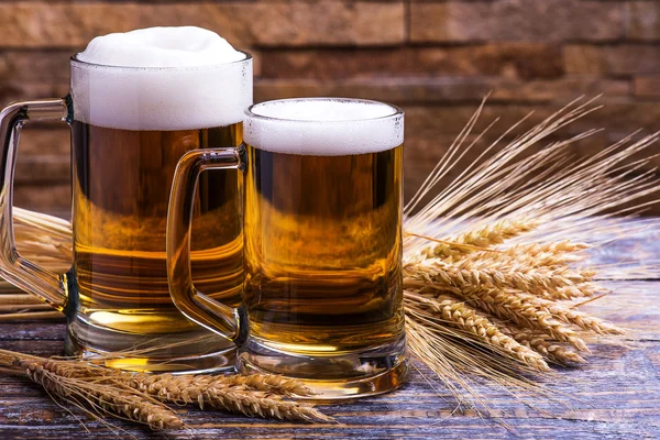 Beer light in a mug, ears of wheat and barley on a wooden dark background
