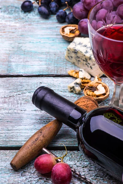 Botella de vino tinto, copa de vino de uvas rosadas, queso, nueces, sacacorchos sobre fondo de mesa de madera —  Fotos de Stock