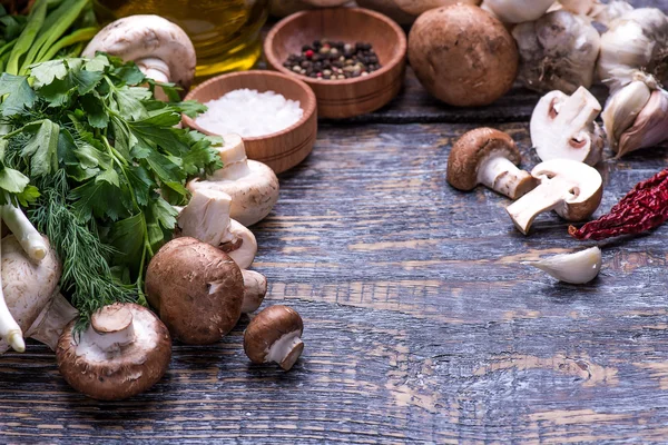 Mushrooms, parsley, dill, onion, olive oil, spices - ingredients for the preparation of mushroom dishes in a frying pan on a wooden background — Stock Photo, Image