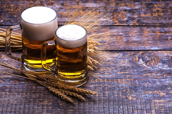 Beer light in a mug, ears of barley, wheat, isolated on wooden background
