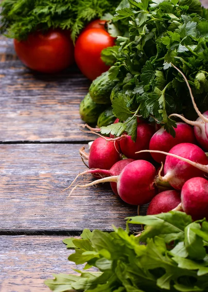 Bahar sebze ve otlar bir sepet içinde: turp, soğan, maydanoz, bir ahşap zemin üzerine salatalık.