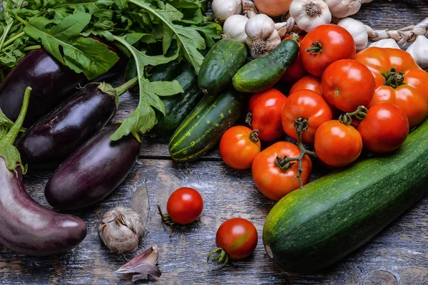 Cosecha Hortalizas: tomates, pepinos, calabacín, berenjena, cebolla, ajo, rúcula sobre el fondo de madera —  Fotos de Stock