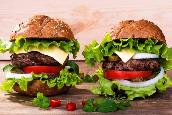 Großer Hamburger mit Rinderschnitzel und Gemüse auf Holzteller — Stockfoto