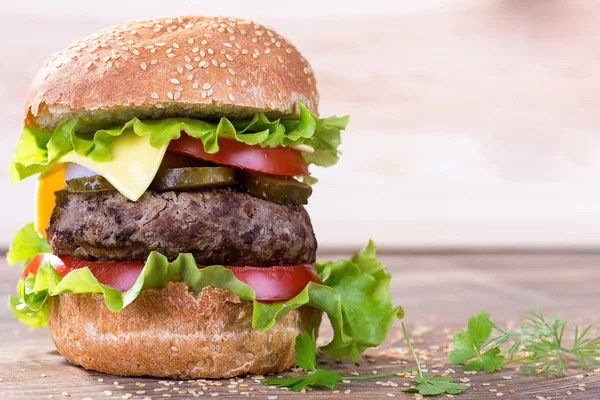 Großer Hamburger mit Rinderschnitzel und Gemüse auf Holzteller — Stockfoto