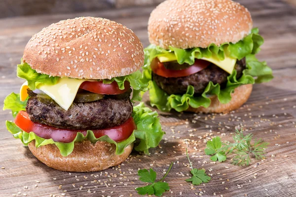 Big hamburger with beef cutlet and vegetables on wood plate