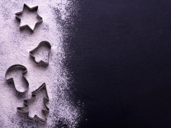 Christmas cookies. Ingredients for baking:  flour, spices, forms for biscuits on black board