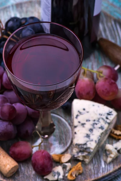 Botella de vino tinto, uvas, nueces y queso sobre fondo de madera —  Fotos de Stock