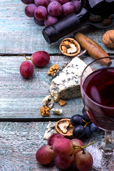 Botella de vino tinto, uvas, nueces y queso sobre fondo de madera —  Fotos de Stock