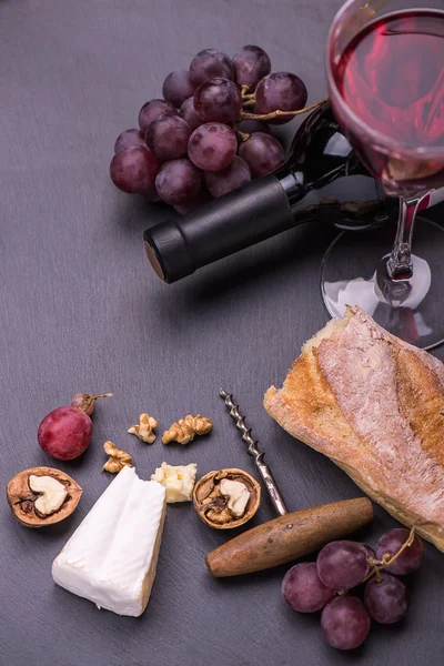 Botella de vino tinto, uvas, nueces y queso sobre fondo de madera —  Fotos de Stock