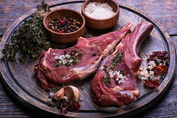 Ham sığır eti biftek, tuz, biber, sarımsak, biberiye kara tahta, arka plan üzerinde.