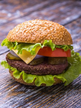 Dana pirzola, hamburger taze sebze: domates, soğan, marul, sos ve susam ahşap zemin ile topuz