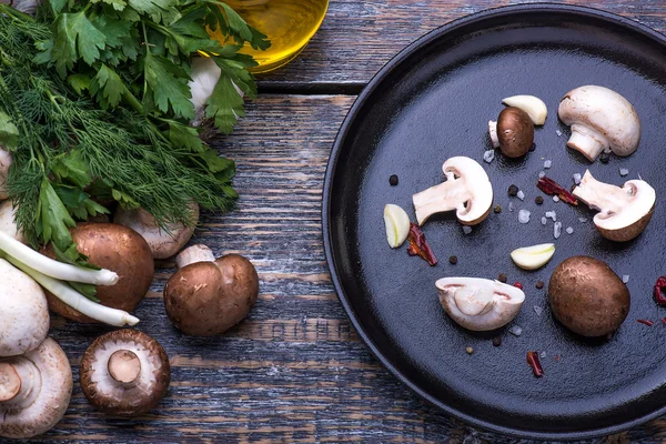Гриби, петрушка, кріп, цибуля, оливкова олія, спеції - інгредієнти для приготування грибних страв на сковороді на дерев'яному фоні — стокове фото