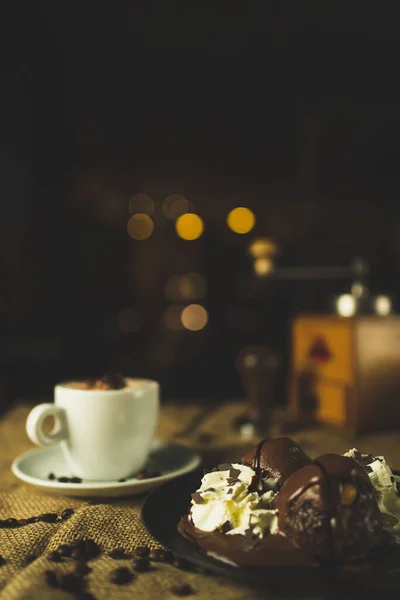 Bir fincan kahve ve çöl, kapuçino. Kahve öğütücüsüyle, espresso makinesiyle ve çikolatayla güzel bir kompozisyon. Restoran ve kahve dükkanı. Güzel kremalı bokeh..
