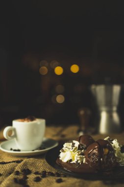 Bir fincan kahve ve çöl, kapuçino. Kahve öğütücüsüyle, espresso makinesiyle ve çikolatayla güzel bir kompozisyon. Restoran ve kahve dükkanı. Güzel kremalı bokeh..