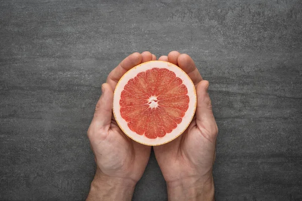 Greyfurt tutan iki erkek el. Bol vitaminli ve güzel renkte taze turunçgiller..