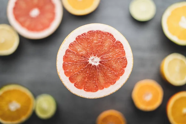 Arka planda bir sürü sağlıklı turunçgil meyvesi olan bir greyfurt. Güzel renkleri olan yeni bir vitamin bileşimi..