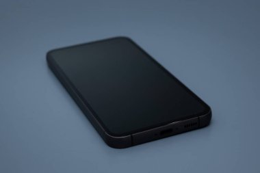 Mavi yüzeye yerleştirilmiş koyu ekran telefon teknoloji ve reklam sunumları kavramına uyuyor.