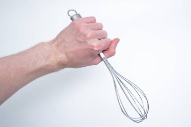 Erkek el paslanmaz çelik çırpıcıyı sıkıca kavrıyor, temiz ışık arka planında sallanıyor, kaliteyi ve yemek pişirme kolaylığını vurguluyor..