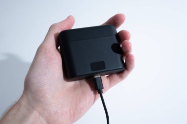 Siyah USB-C kablosunu gri masadaki kablosuz kulaklıklara bağlıyorum..