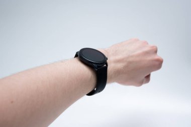 Erkek bileğine takılan yuvarlak ekran, hafif arka planda gevşek eller, stili ve teknolojiyi sembolize ediyor..