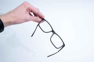 İnsan eli dikkatle siyah çerçeveli bardakları açık, sert bir kutunun üzerinde ışığın üzerinde tutuyor..