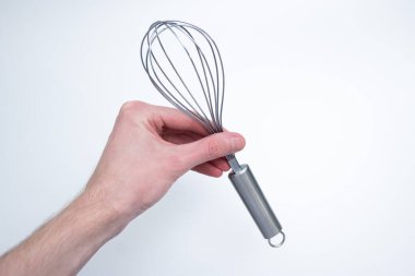 Erkek el paslanmaz çelik çırpıcıyı sıkıca kavrıyor, temiz ışık arka planında sallanıyor, kaliteyi ve yemek pişirme kolaylığını vurguluyor..