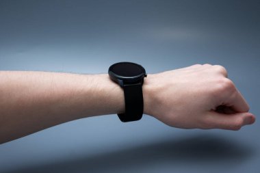 Erkek bileğine takılan yuvarlak ekran, hafif arka planda gevşek eller, stili ve teknolojiyi sembolize ediyor..