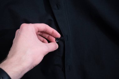 Askıda asılı siyah gömlek, içinde mor etiketi göstermek için el çekme tasması..