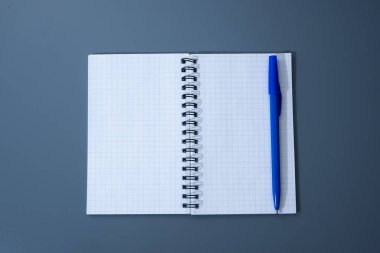 Gri masadaki notlar ve fikirler için hazır parlak mavi kalemli temiz spiral grafik defteri..