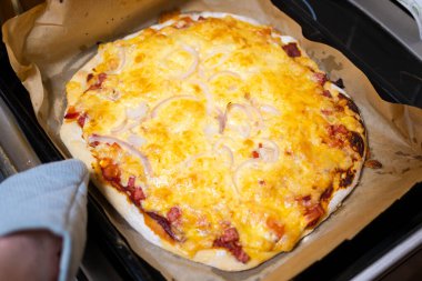 Fırından yeni çıkarılmış sosisli, peynirli ve soğan halkalı ev yapımı pizza..