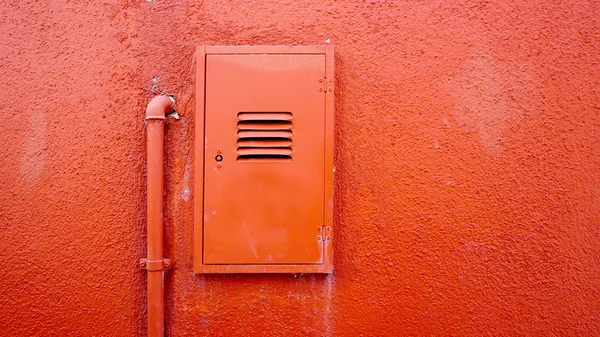 Metallrohr und Stromkasten auf orangefarbener Wand — Stockfoto