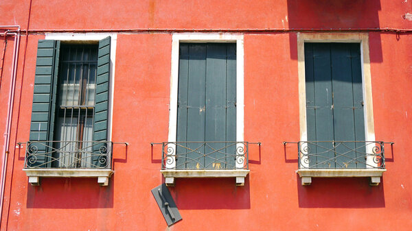 Three wiindows on orange wall building in Venice, Italy