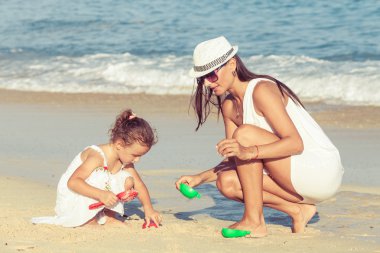 Anne ve kızı kumsalda gün anda oynamak.