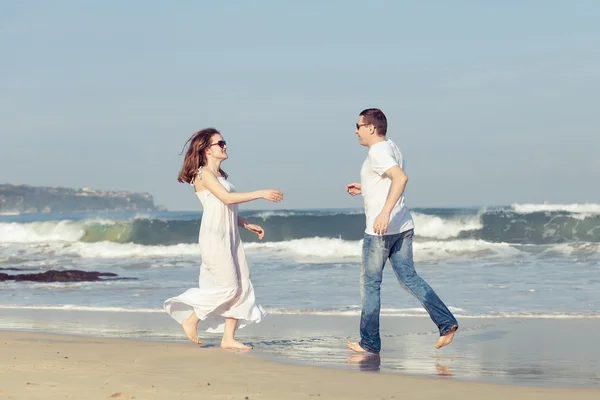 Casal amoroso correndo na praia na hora do dia . — Fotografia de Stock