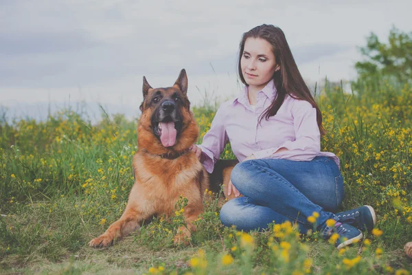 Junges schönes Mädchen mit einem Schäferhund, der auf dem Rasen spielt — Stockfoto