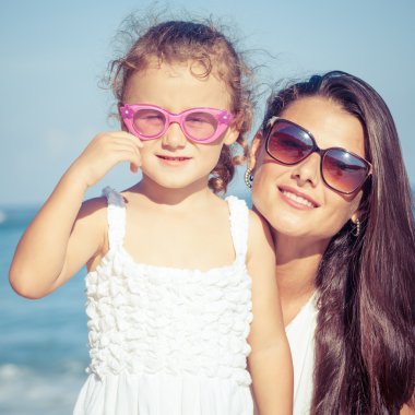 Anne ve kızı kumsalda gün anda oynamak.