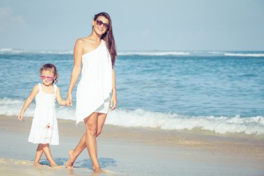 Anne ve kızı kumsalda gün anda oynamak.