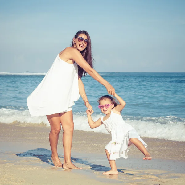 Anne ve kızı kumsalda gün anda oynamak.