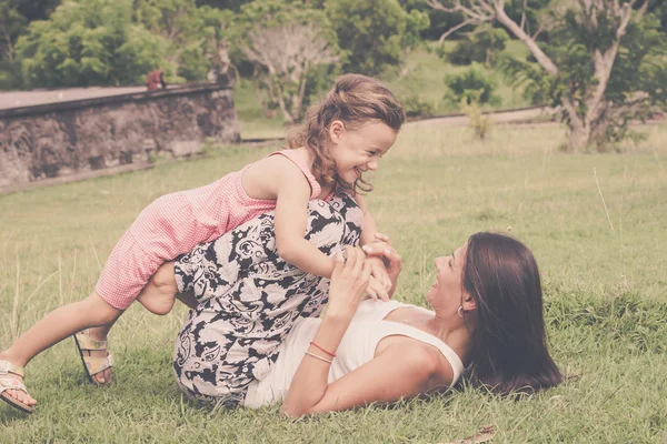 Mother and daughter playing on the grass at the day time. — Stock Photo, Image