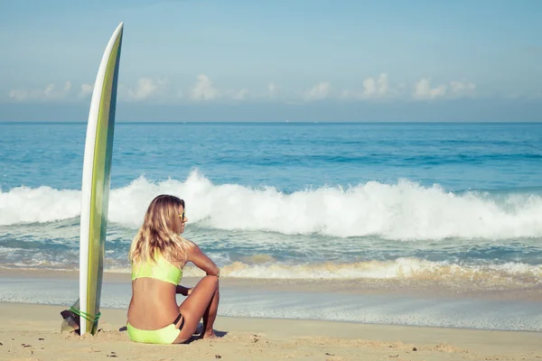 Schöne Surfermädchen sitzt am Strand — Stockfoto
