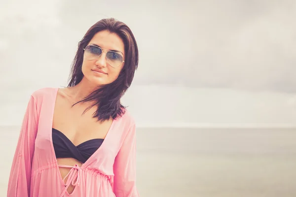 Retrato de una hermosa chica morena en gafas de sol en la playa — Foto de Stock