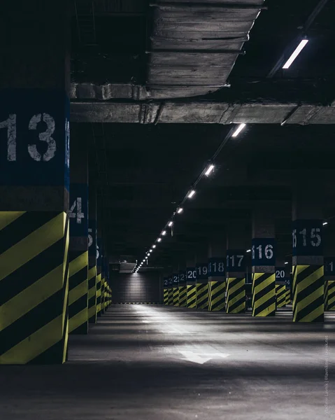 Süpermarketin altındaki yeraltı otoparkı, yeşil siyah çizgilerle boyanmış direkler.